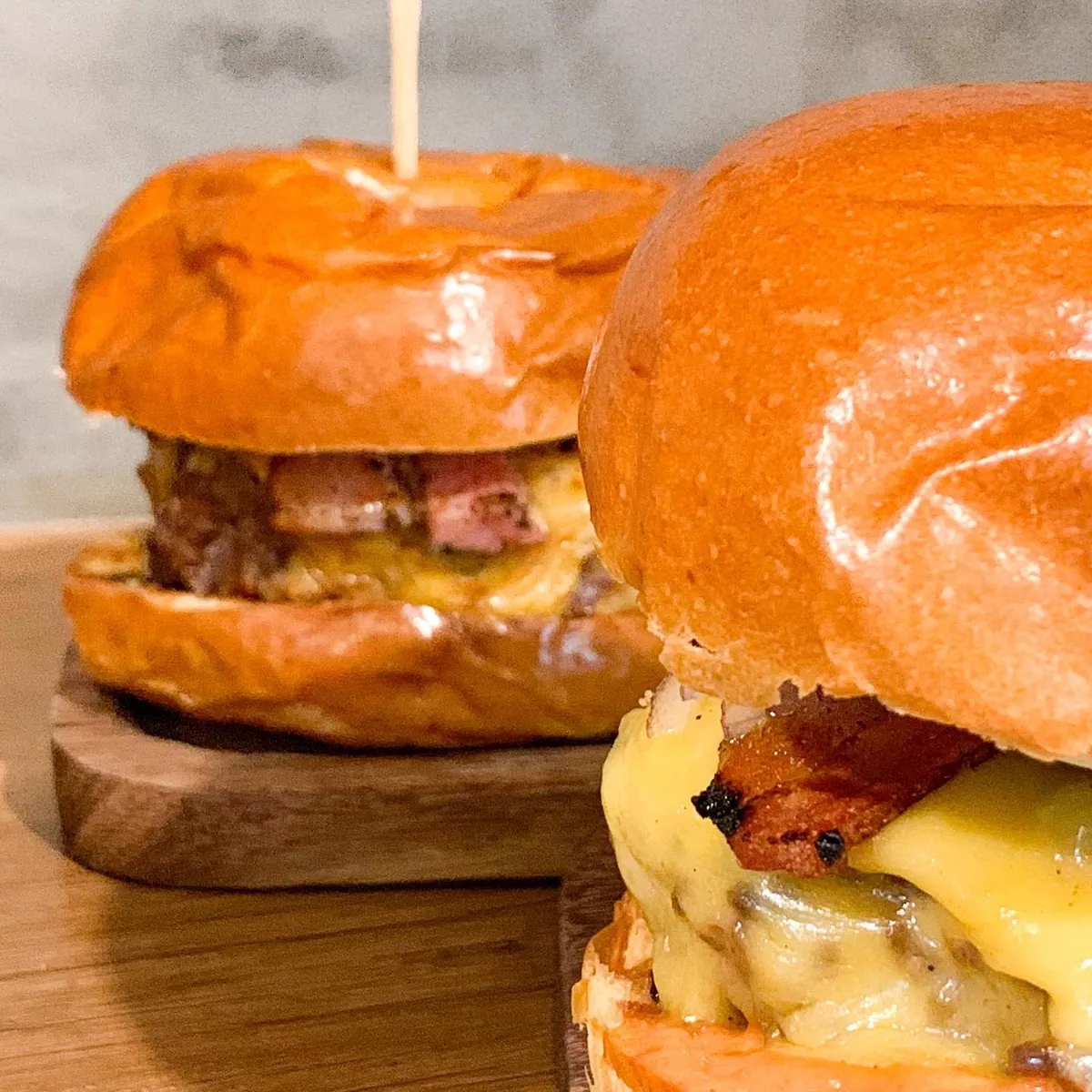 Dois hambúrgueres com queijo derretido e bacon, em fotos públicas ligadas à casa