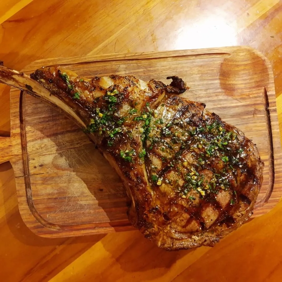 Tomahawk cru no balcão refrigerado, ao lado de outros cortes